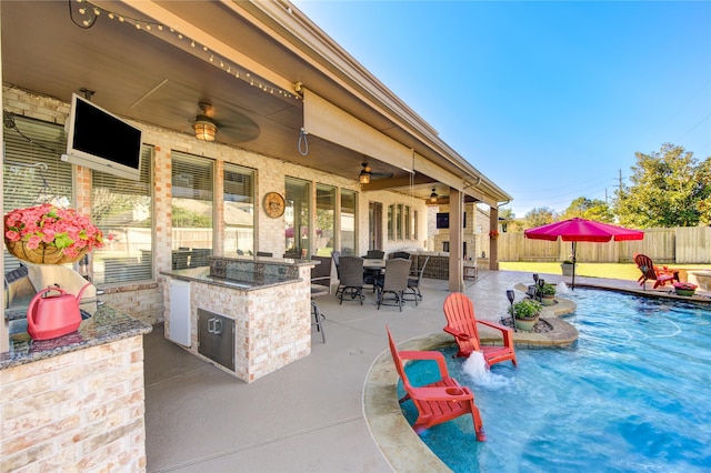 view of patio / terrace featuring exterior bar, a fenced in pool, ceiling fan, and exterior kitchen