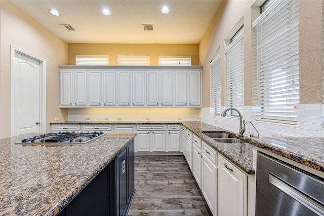 kitchen featuring sink, dark wood-type flooring, stainless steel gas cooktop, dark stone counters, and white cabinets