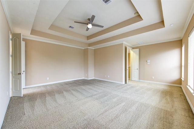 unfurnished room with carpet floors, a tray ceiling, a wealth of natural light, and ornamental molding