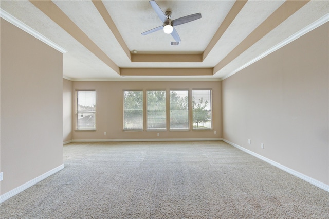 spare room with a tray ceiling, ceiling fan, light carpet, and ornamental molding