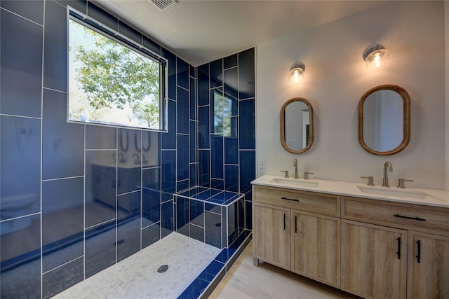 bathroom featuring a tile shower and vanity