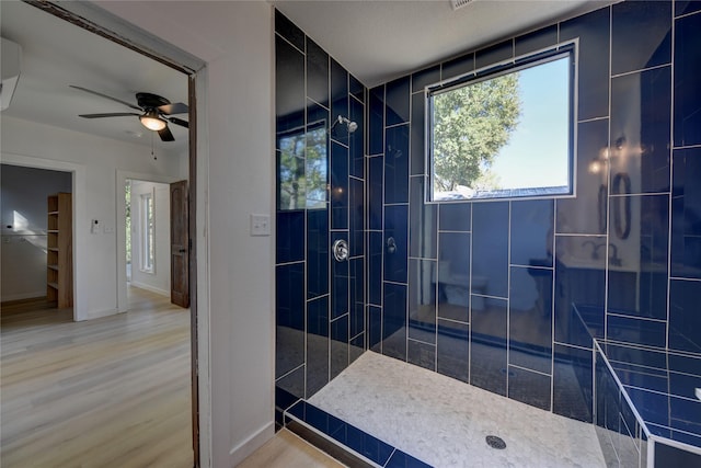 bathroom featuring a tile shower, ceiling fan, and wood-type flooring