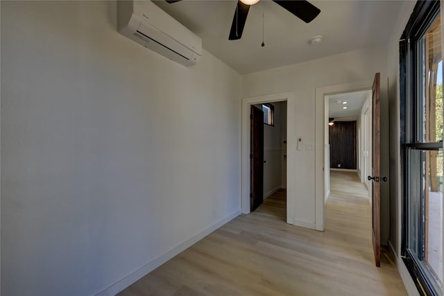 spare room featuring light hardwood / wood-style floors, an AC wall unit, and ceiling fan