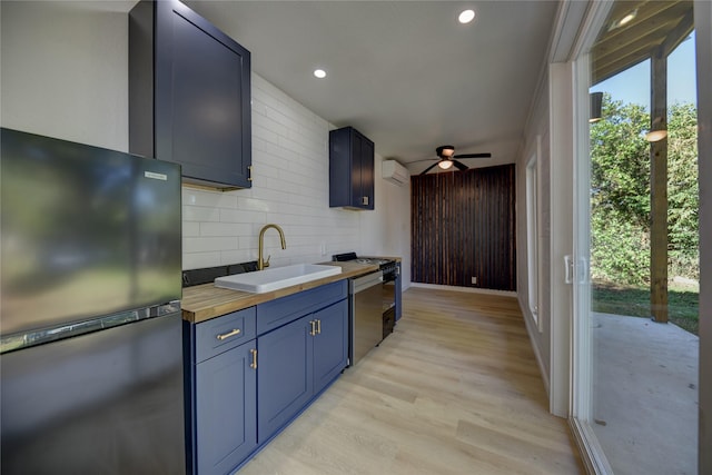 kitchen with ceiling fan, sink, stainless steel appliances, wood counters, and a wall mounted AC