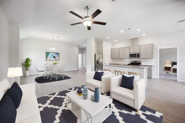 living room featuring light wood-type flooring, vaulted ceiling, and ceiling fan