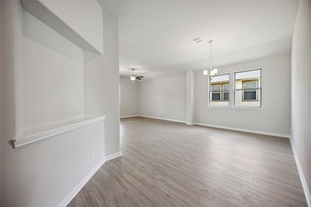 spare room with ceiling fan with notable chandelier and hardwood / wood-style flooring