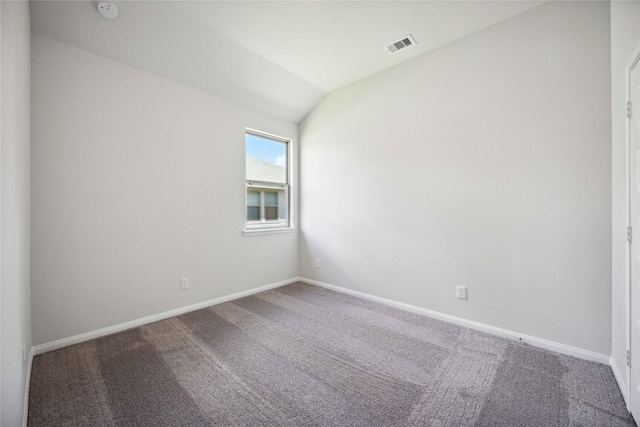 carpeted spare room featuring vaulted ceiling