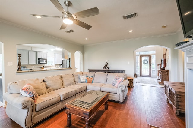 living room with dark hardwood / wood-style floors, ceiling fan, and crown molding