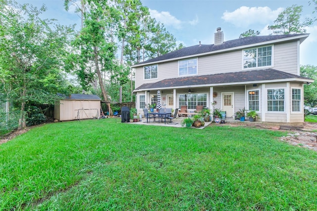 rear view of house featuring a storage unit, a yard, and a patio