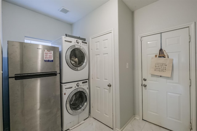 washroom with stacked washer / drying machine and light tile patterned flooring