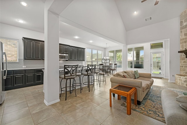 living room featuring ceiling fan, light tile patterned flooring, and high vaulted ceiling