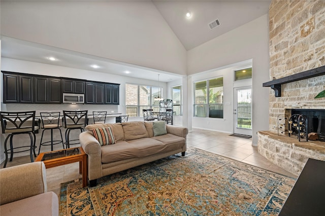 living room featuring light tile patterned flooring, a fireplace, and high vaulted ceiling