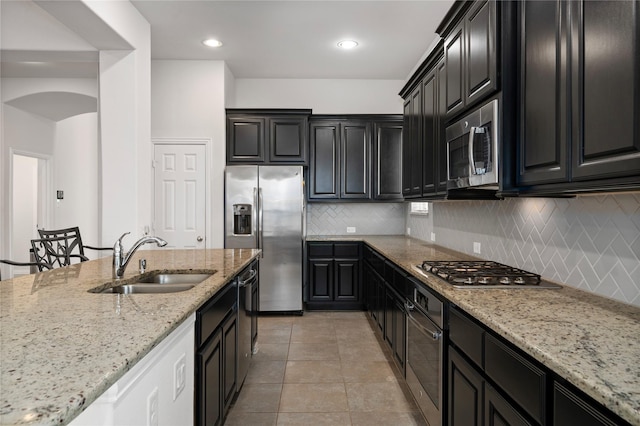 kitchen with decorative backsplash, light stone counters, sink, and appliances with stainless steel finishes