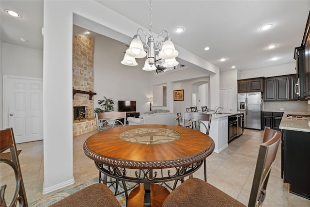 tiled dining room featuring a fireplace, a notable chandelier, and sink