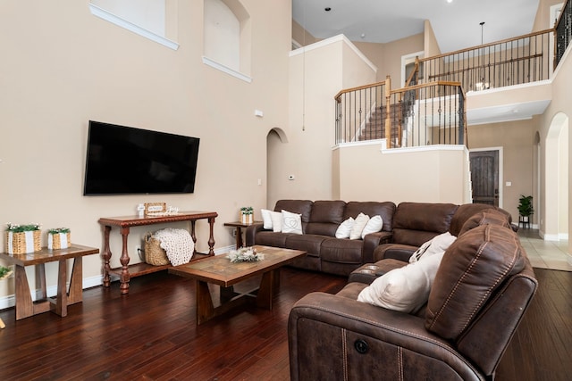 living room with a towering ceiling and dark hardwood / wood-style floors