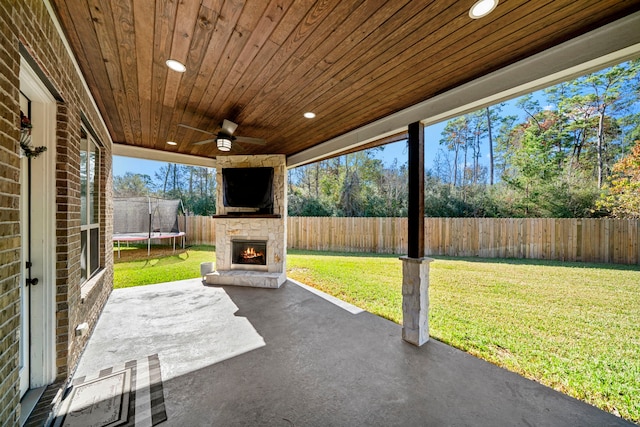 view of patio / terrace featuring an outdoor stone fireplace, ceiling fan, and a trampoline