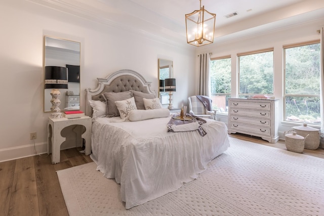 bedroom featuring hardwood / wood-style floors, crown molding, and a chandelier