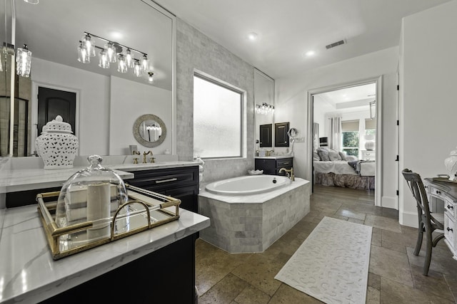 bathroom with tiled tub and vanity