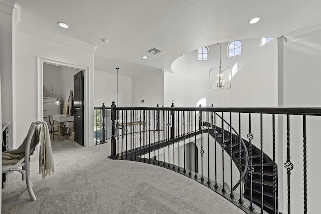 hallway with an inviting chandelier, carpet floors, and crown molding