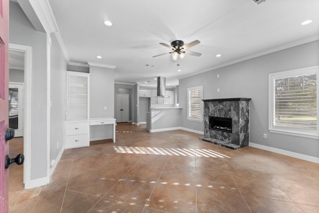 unfurnished living room with a high end fireplace, dark tile patterned flooring, ceiling fan, and ornamental molding