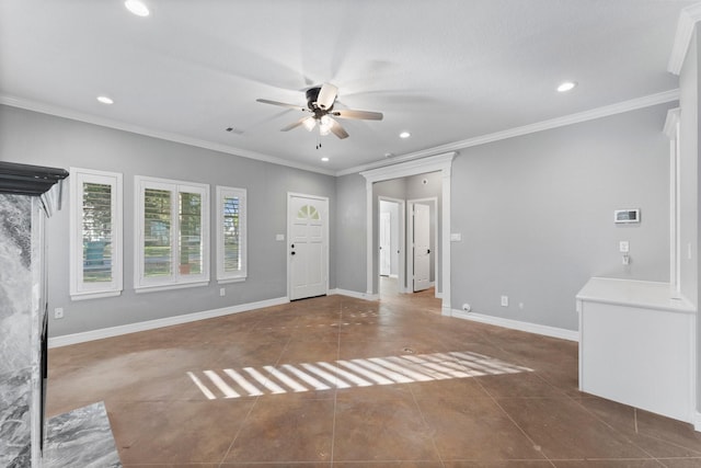 unfurnished living room with dark tile patterned floors, ornamental molding, and ceiling fan