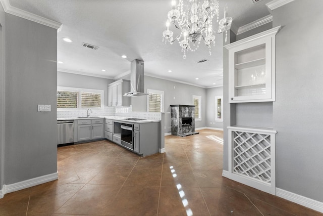 kitchen with a high end fireplace, wall chimney exhaust hood, stainless steel appliances, sink, and gray cabinets