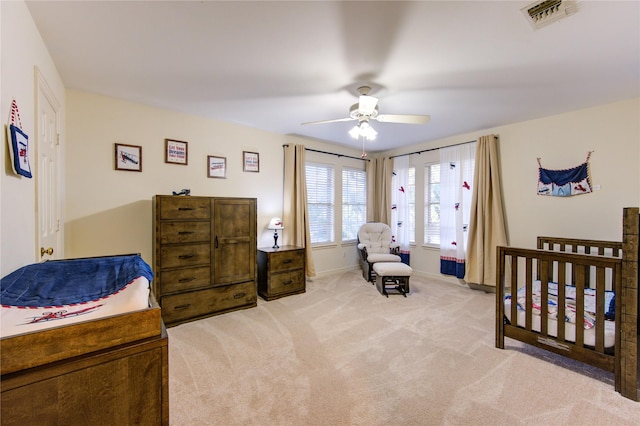 carpeted bedroom with a nursery area and ceiling fan