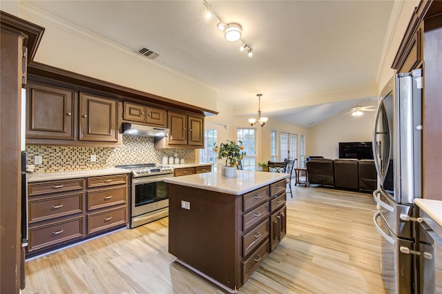 kitchen featuring a center island, lofted ceiling, tasteful backsplash, decorative light fixtures, and stainless steel appliances