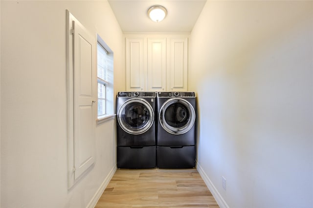 clothes washing area with light hardwood / wood-style floors, cabinets, and separate washer and dryer