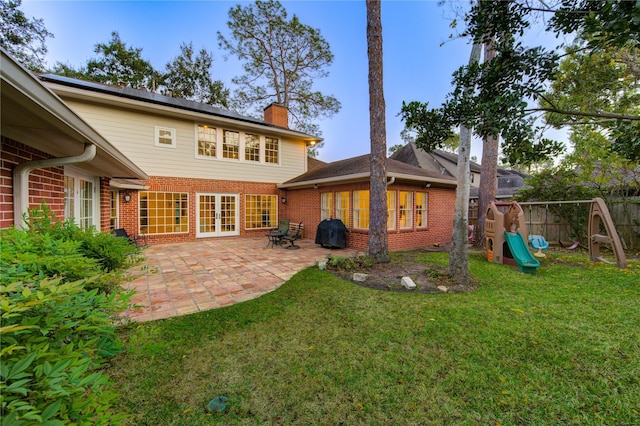 back of house with a patio area, a playground, and a yard