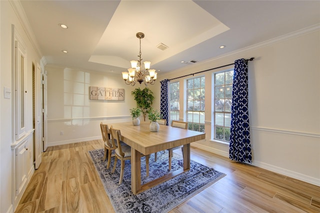 dining room with a tray ceiling, ornamental molding, and light hardwood / wood-style floors