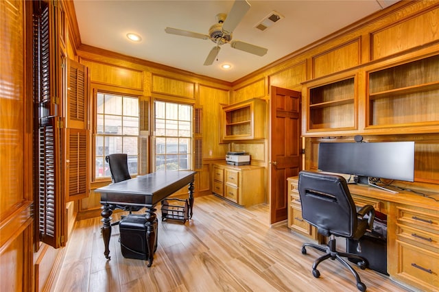 office area with ceiling fan, wood walls, light wood-type flooring, and ornamental molding