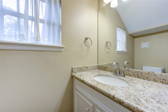 bathroom with vanity, toilet, and lofted ceiling