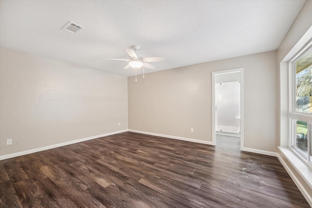 empty room with ceiling fan, dark wood-type flooring, and a wealth of natural light