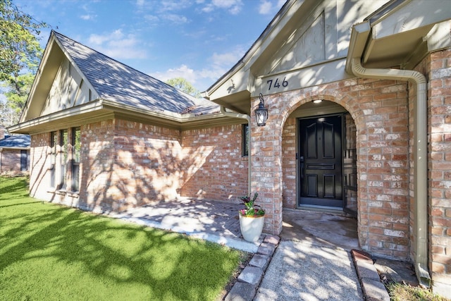 view of exterior entry featuring a lawn