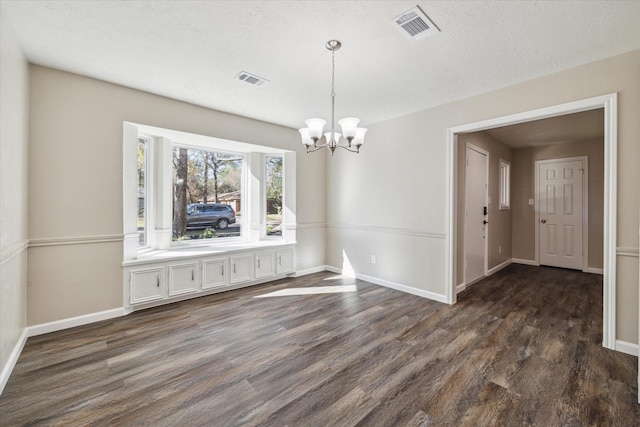 unfurnished dining area featuring dark hardwood / wood-style flooring, a textured ceiling, and a notable chandelier