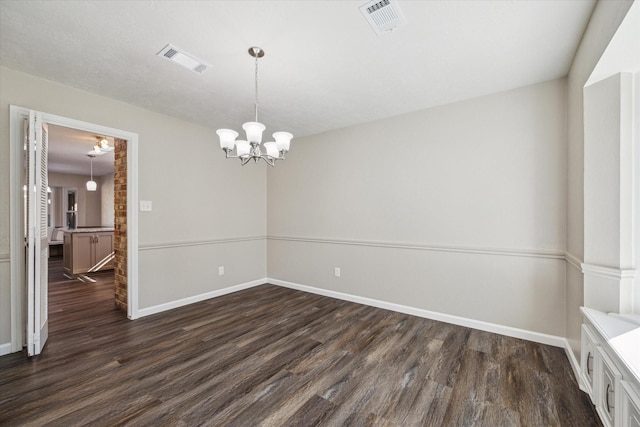 empty room with dark wood-type flooring and an inviting chandelier