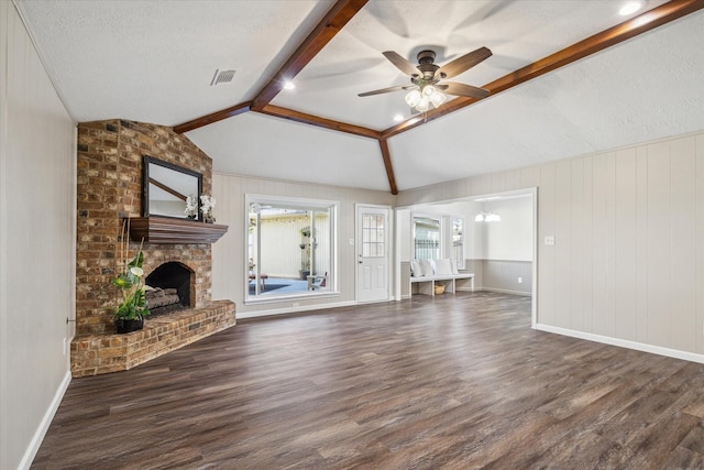 unfurnished living room with a brick fireplace, ceiling fan with notable chandelier, a textured ceiling, lofted ceiling with beams, and dark hardwood / wood-style floors