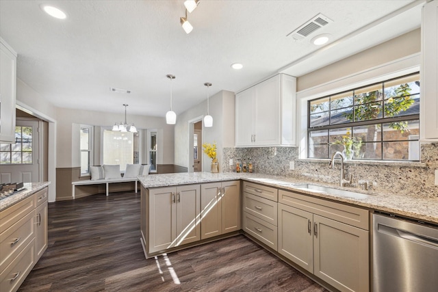 kitchen with light stone countertops, dishwasher, sink, kitchen peninsula, and a chandelier