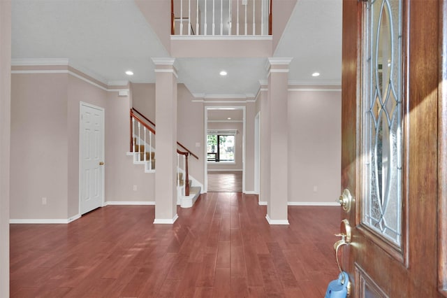 foyer entrance featuring dark hardwood / wood-style flooring, ornamental molding, and decorative columns