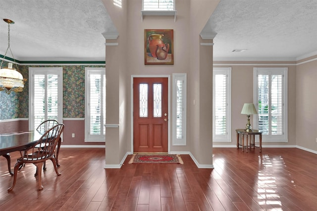 foyer with an inviting chandelier, dark wood-type flooring, and ornamental molding