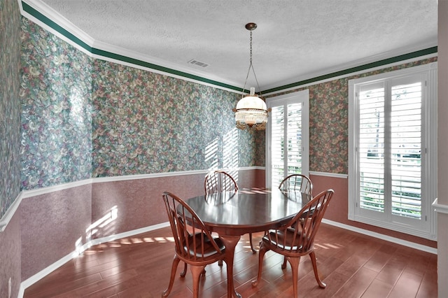 dining area featuring dark hardwood / wood-style flooring, a chandelier, a textured ceiling, and ornamental molding