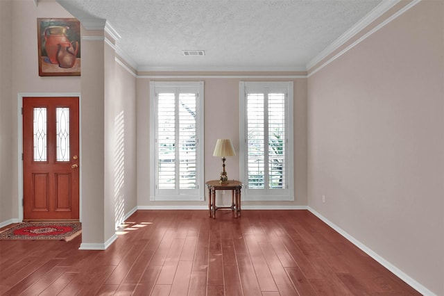 foyer with a textured ceiling, dark wood-type flooring, and ornamental molding