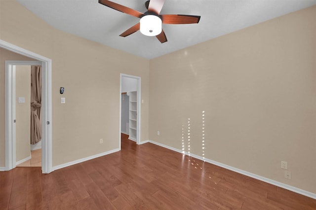 unfurnished bedroom featuring wood-type flooring, a closet, a spacious closet, and ceiling fan