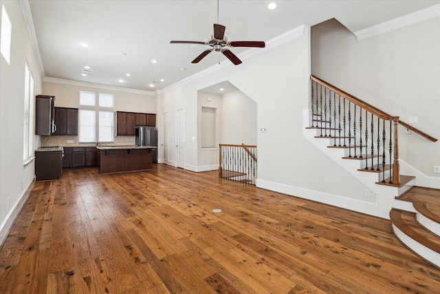 unfurnished living room with ceiling fan, crown molding, dark wood-type flooring, and sink