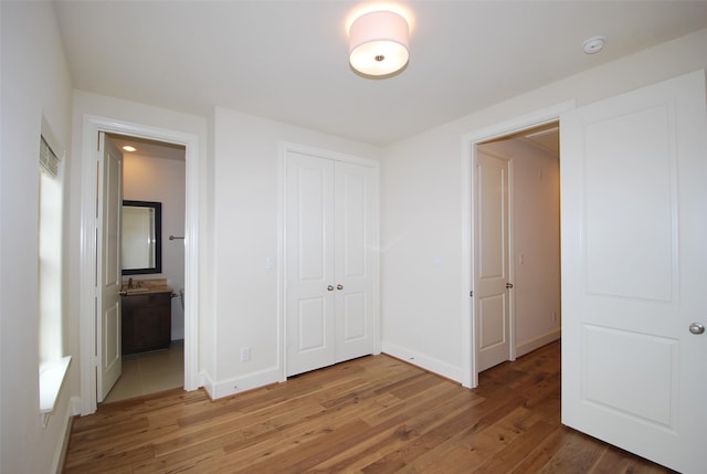 unfurnished bedroom with hardwood / wood-style flooring, ensuite bath, a closet, and sink