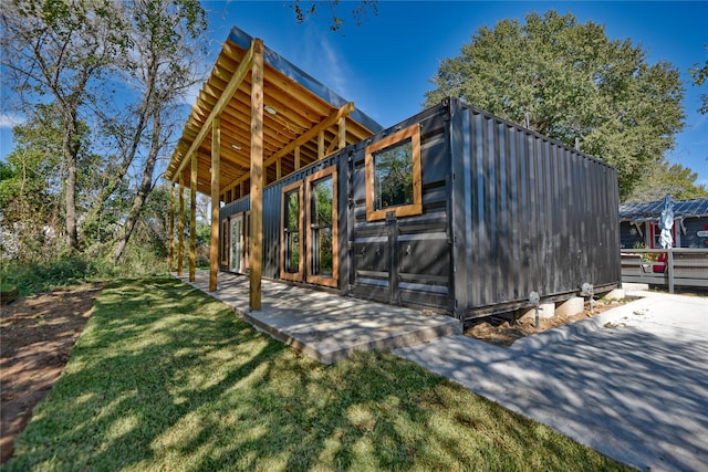 view of home's exterior with a patio area, an outdoor structure, and a lawn