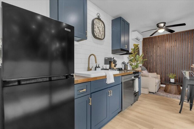 1411 Clay St, Brenham, TX 77833 - kitchen with freestanding refrigerator, blue cabinets, wooden counters, ceiling fan, and wood walls