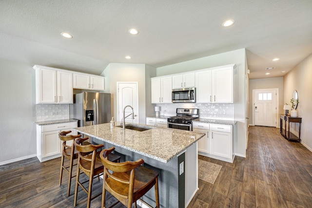 kitchen featuring a kitchen island with sink, white cabinets, sink, light stone countertops, and appliances with stainless steel finishes