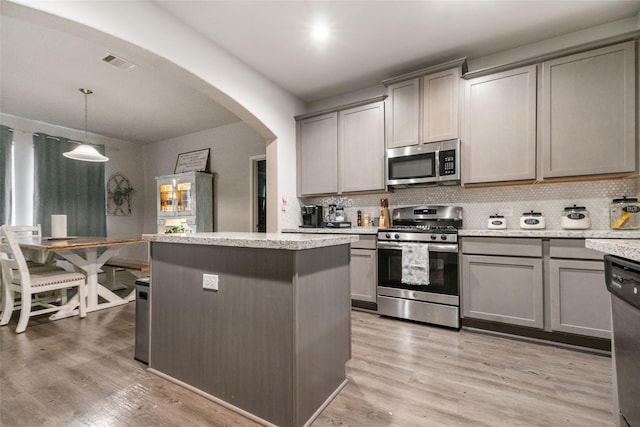 kitchen with appliances with stainless steel finishes, hanging light fixtures, gray cabinets, and tasteful backsplash